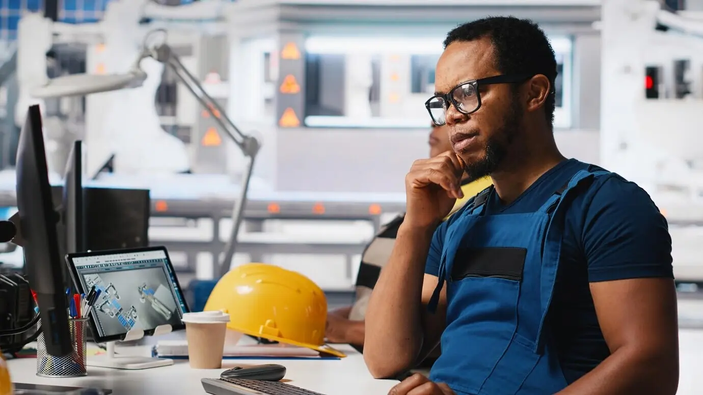 Ein schwarzer Ingenieur führt Diagnosetests an der Software für die Montage von Solarmodulen durch, die die Produktion optimiert.